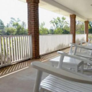 A peaceful porch with rocking chairs and a view of trees.