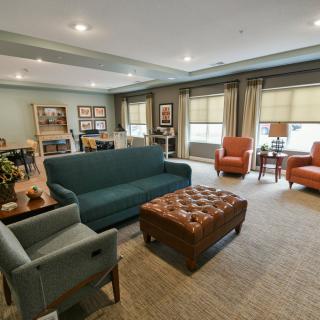 A cozy living room with a sofa, armchairs, and a coffee table, featuring warm decor and ample natural light.