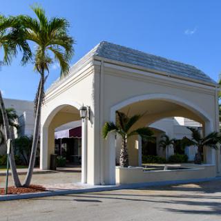 A welcoming entrance with palm trees under a clear blue sky.