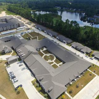 Aerial view of a large building complex surrounded by greenery and a nearby lake.