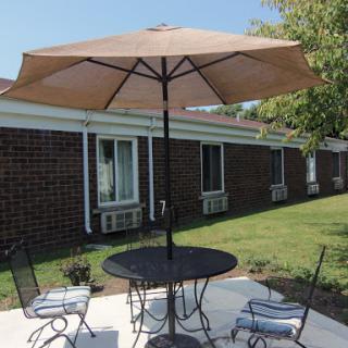 A cozy outdoor seating area with a table, chairs, and a large umbrella for shade.