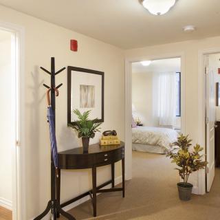 A cozy hallway with a side table, coat rack, and decorative plants.