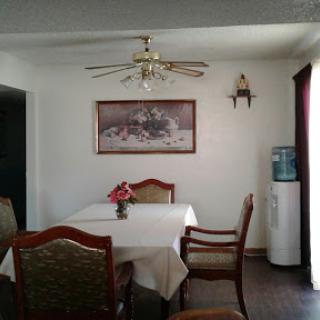 A cozy dining room setup featuring a table with floral decorations and a water cooler.