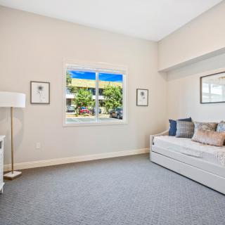 A bright and modern living room featuring minimalist decor with neutral colors, showcasing a comfortable sofa and a window with a view of greenery outside.