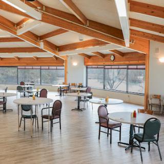 A spacious dining area featuring modern architecture with wooden beams and abundant natural light.