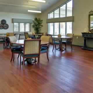 A well-lit dining room with hardwood floors, tables, and chairs arranged neatly.