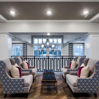 A modern living room with stylish armchairs and a central coffee table, accented by decorative pillows and ceiling lights.