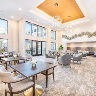 A modern lounge area with elegant furniture, large windows, and stylish chandeliers.