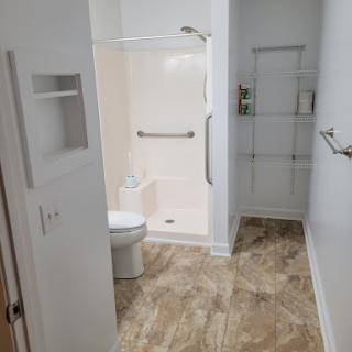 A modern bathroom featuring a shower, toilet, and functional storage.