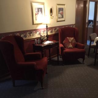 A cozy seating area with two red armchairs, a lamp, and wall decorations.