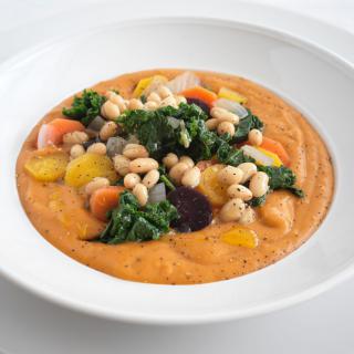 A colorful vegetable and bean soup served in a white bowl.