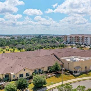 Aerial view of a residential building surrounded by greenery under a cloudy sky.