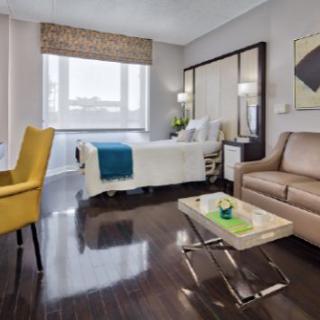 A modern hospital room featuring a single bed, comfortable seating area, and ample natural light.