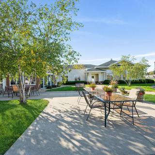 A spacious patio with outdoor furniture and trees in a sunny garden setting.