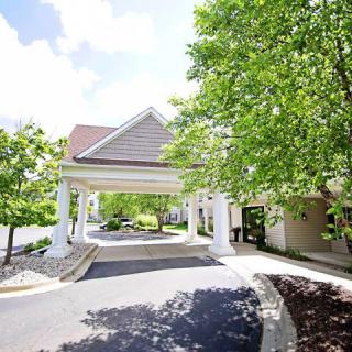 A building entrance with a covered driveway surrounded by trees.
