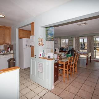 An open floor plan kitchen and dining area with tiled floors and wooden furniture.
