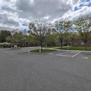 A peaceful parking lot surrounded by trees under a cloudy sky.