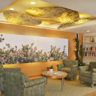 A cozy lobby with comfortable seating, floral artwork, and a bookshelf.