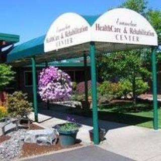 Entrance of a healthcare and rehabilitation center with an awning and landscaped surroundings.