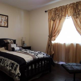 A cozy bedroom with dark furniture, decorative bedding, and elegant curtains.