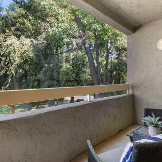 A cozy balcony overlooking a lush green area with outdoor furniture.