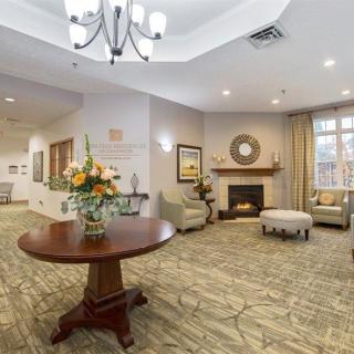 A cozy and elegantly decorated living room featuring a fireplace, comfortable seating, and a chandelier.