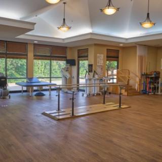 A spacious physical therapy room equipped with parallel bars and exercise tables.