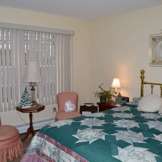 A cozy bedroom with a quilt-covered bed, adorned with warm lighting and vintage decor.