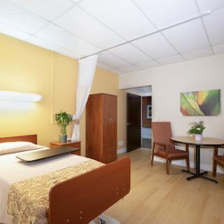 A spacious and well-lit room featuring a bed, a small dining area, and warm-colored walls.