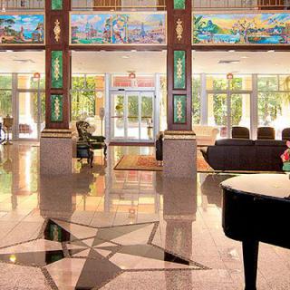 Luxurious hotel lobby with a grand piano and stained glass decorations.