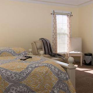 A cozy bedroom with a patterned bedspread and ample natural light.