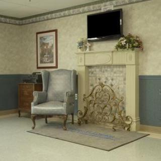A cozy living room with an armchair, television, and fireplace.