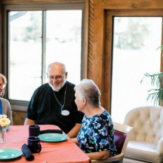 A group of seniors enjoying a meal and conversation together indoors.