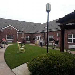 A courtyard with a lawn and pathway surrounded by a brick building, with people enjoying the outdoor space.
