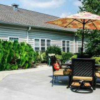 A sunny patio with outdoor furniture and an umbrella in a residential backyard.