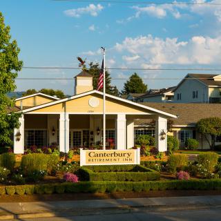 A retirement community with well-maintained gardens and an American flag at the entrance.