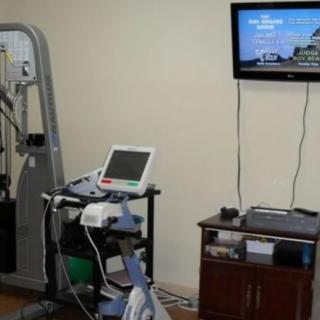 A medical room equipped with an EKG machine, exercise equipment, and a television.