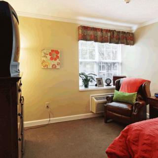 Cozy bedroom with an armchair and a television near the window.