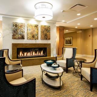 A modern living room with elegant seating, a central fireplace, and decorative art on the walls.