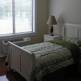 A cozy bedroom with a single bed, nightstand, and window with blinds.