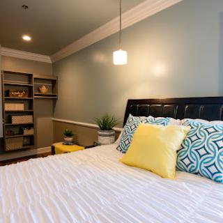 A cozy and modern bedroom featuring stylish decor, comfortable bedding, and a well-organized bookshelf.