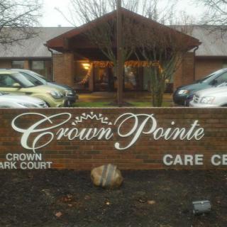 The image shows the entrance of the Crown Pointe Care Center with a prominent sign in front.