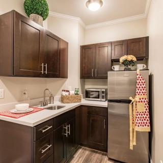 A modern kitchen with wood cabinets and stainless steel appliances in a small, well-organized space.