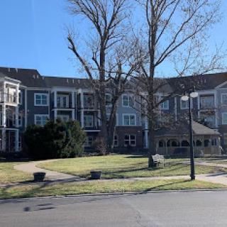 A view of an apartment complex surrounded by trees and clear blue skies.