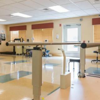 A well-equipped physical therapy room with parallel bars and exercise equipment.