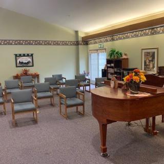 A cozy room with a grand piano and seating arrangements, adorned with a flower centerpiece.