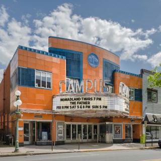 A historic cinema theater with an illuminated marquee on a sunny street.