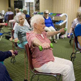 A group of seniors participating in a seated exercise session, focusing on strength and flexibility.
