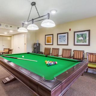 A well-lit recreation room featuring a billiards table with chairs and framed artwork on the walls.