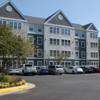 Apartment building with a parking lot and several parked cars.